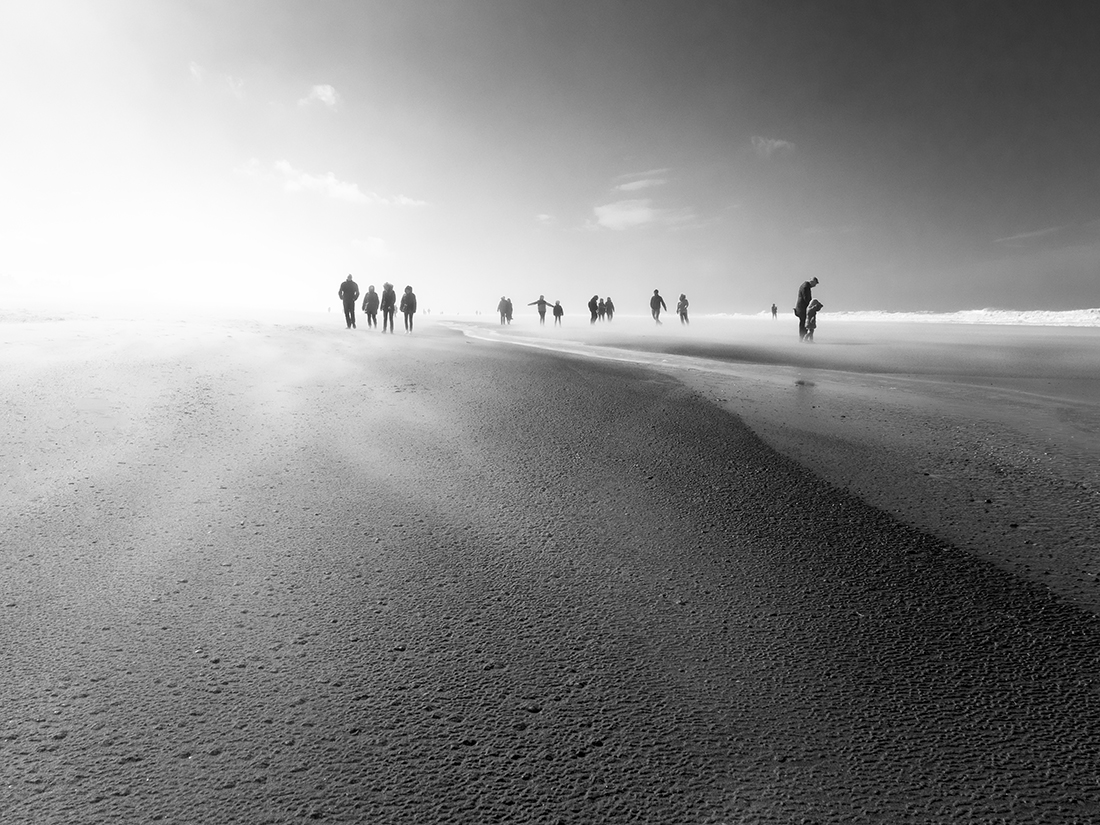 People enjoy stormy weather by the sea.