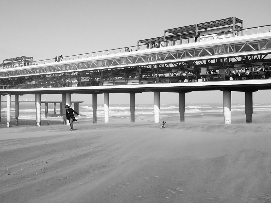 People enjoy stormy weather by the sea.