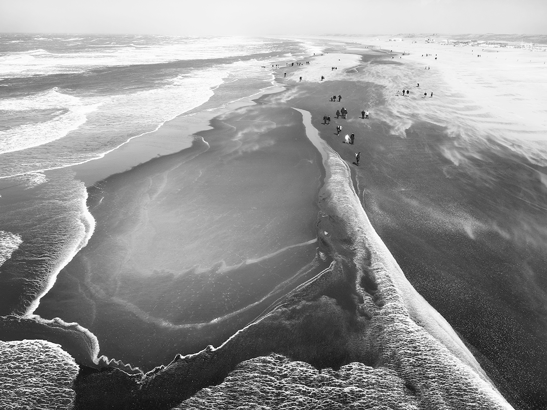 People enjoy stormy weather by the sea.