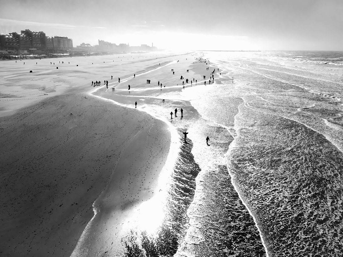People enjoy stormy weather by the sea.
